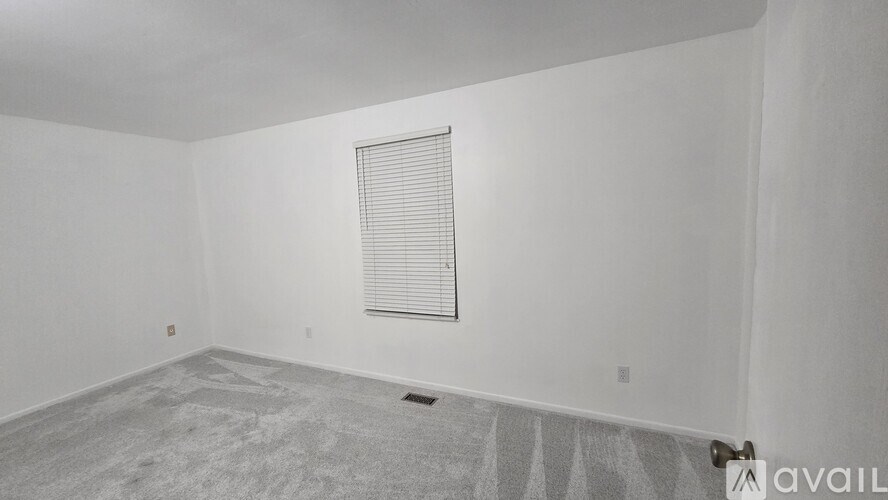A room with a window covered by blinds and a carpet on the floor.
