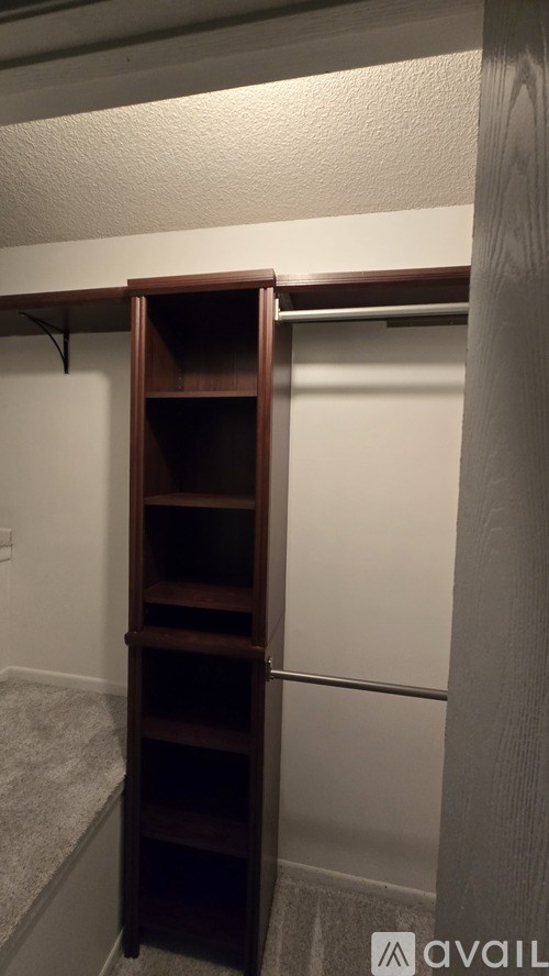 A wooden bookcase with a door open is in a room.