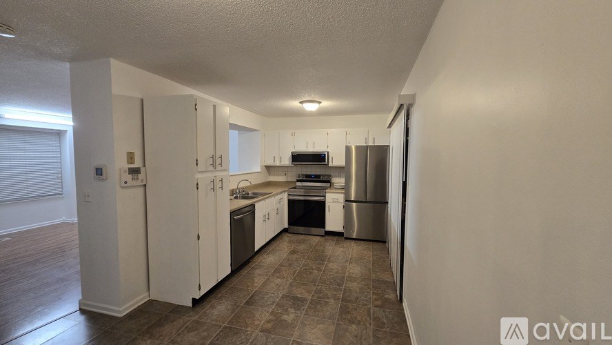 A kitchen with white cabinets and a stainless steel refrigerator.