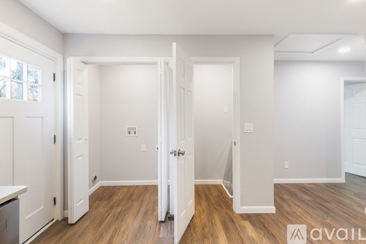A white interior room with a wooden floor and three doors.