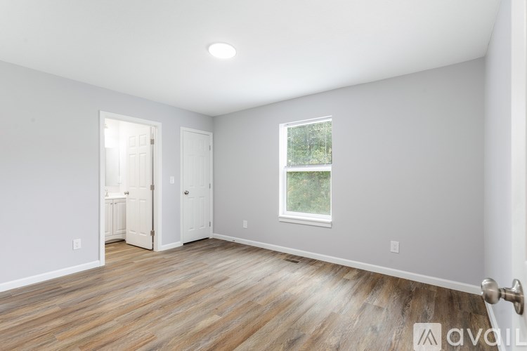 A room with wooden flooring and a window showing greenery outside.