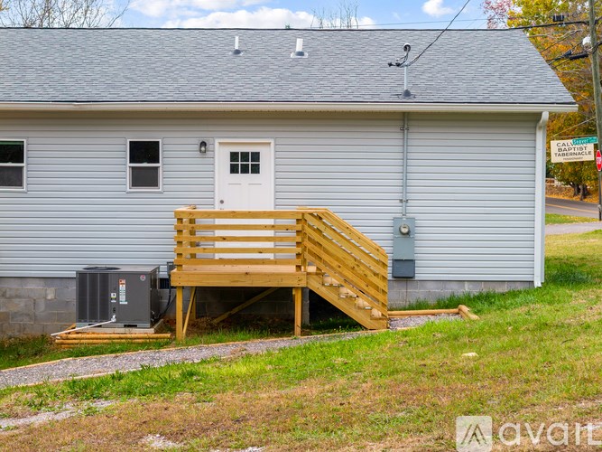 A grey house with a white door and a wooden staircase leading to the front door.