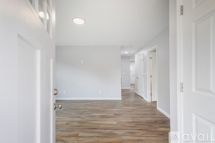 A long hallway with white walls and wood floors.