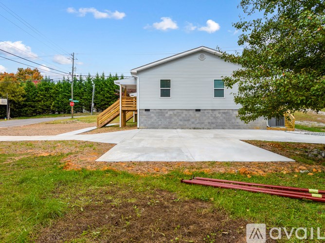 A small house with a grey roof and a wooden staircase leading to the front door.