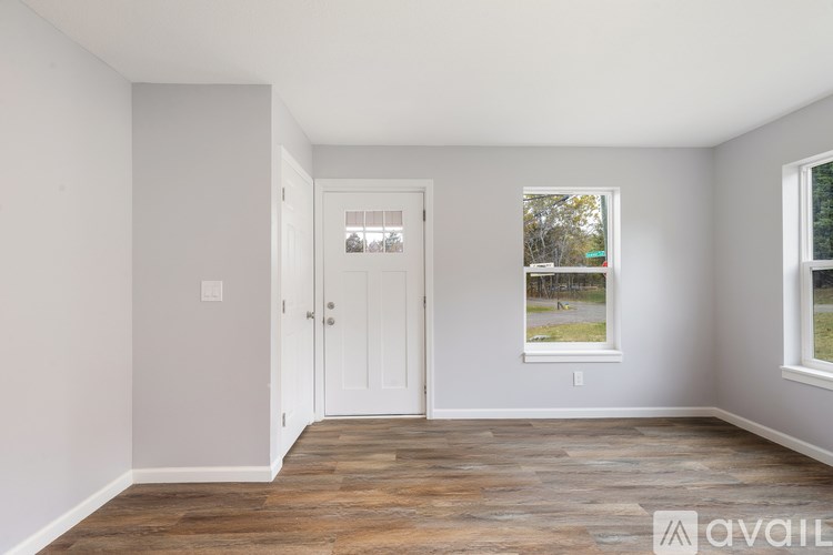A room with a white door and a window with a view of a green field.