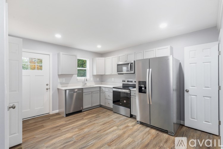 A kitchen with stainless steel appliances and wooden flooring.