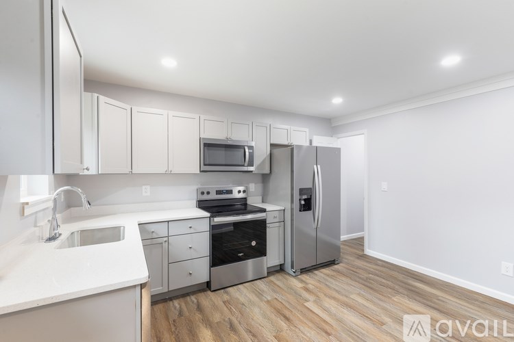 A kitchen with white cabinets and a wooden floor.