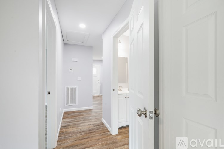 A hallway with white walls and a wooden floor.