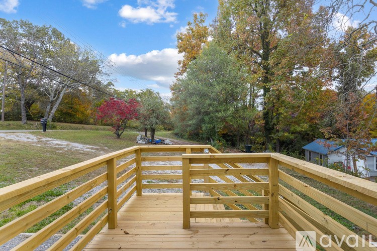 A wooden deck with a railing and a view of a tree-lined path.