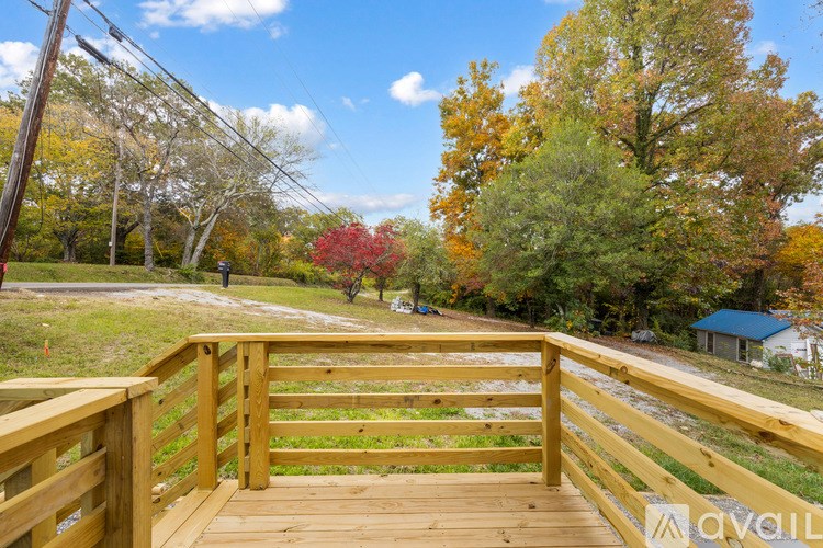 A wooden deck leads to a grassy area with trees in autumn colors.