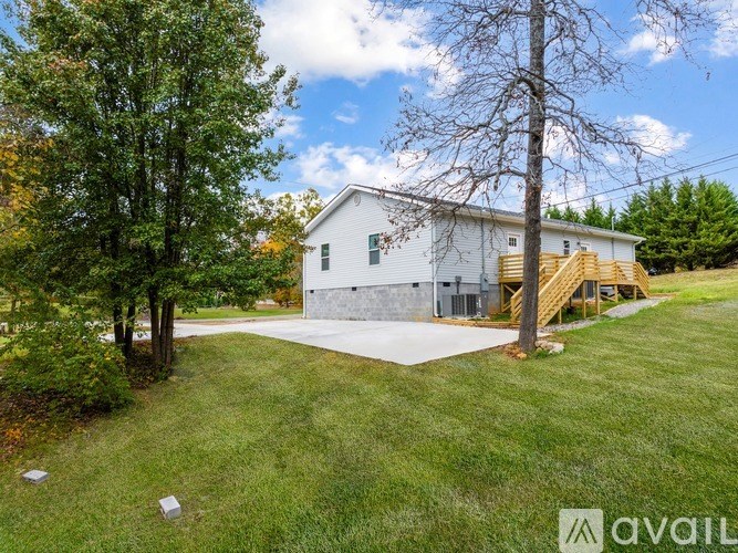 A white house with a grey garage door is surrounded by a grassy lawn and trees.