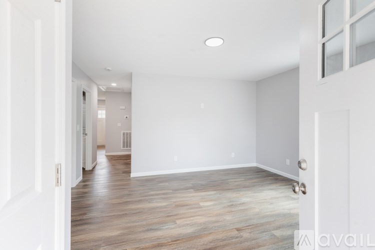 A spacious room with wooden flooring and white walls.