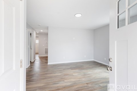 A spacious room with wooden flooring and white walls.