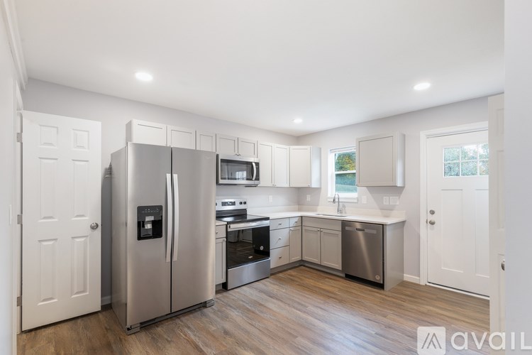 A modern kitchen with stainless steel appliances and wooden flooring.