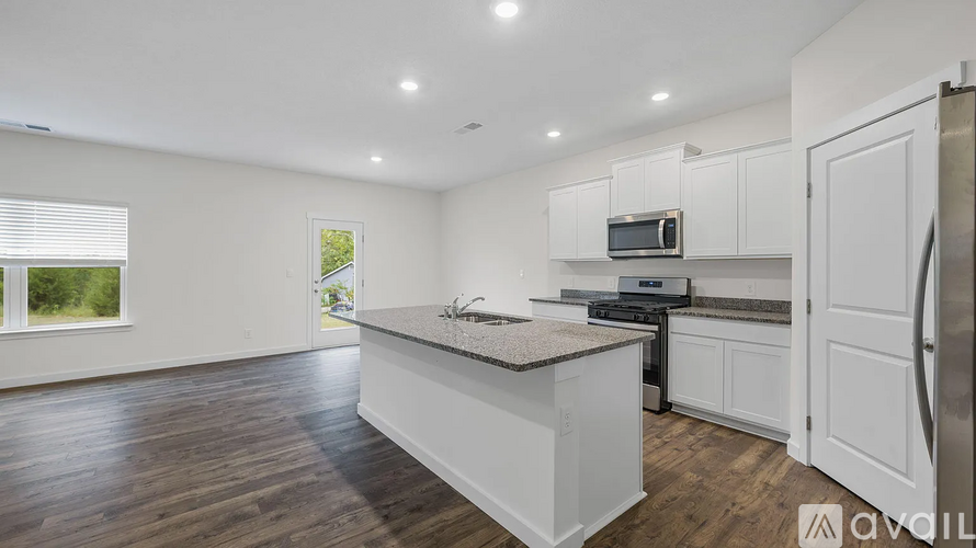 A kitchen with white cabinets and a wooden floor.