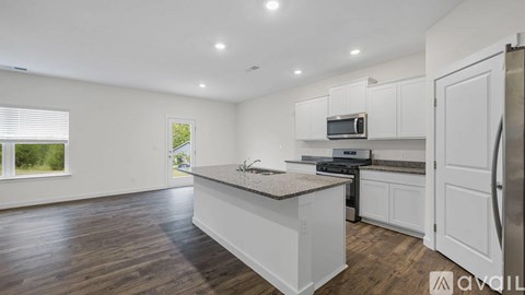 A kitchen with white cabinets and a wooden floor.
