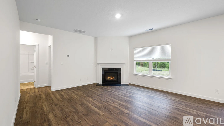 A spacious room with a fireplace and wooden flooring.