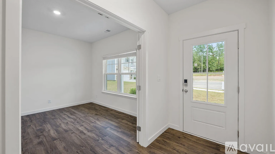 A room with a white door and a window with a view of a building and trees outside.