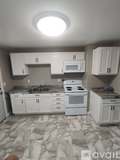 A kitchen with white cabinets and appliances.