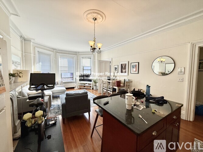 A kitchen with a black countertop and a dining area with a table and chairs.
