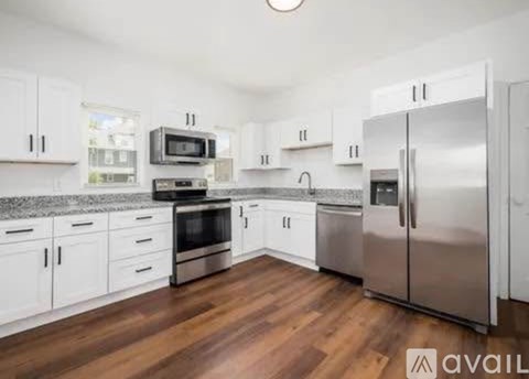 A kitchen with white cabinets and a wooden floor.