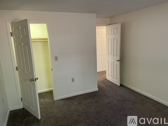 A room with two doors, one open, and carpeted flooring.