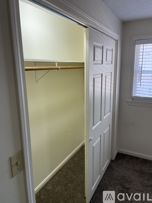 A white door is open to a room with a window.