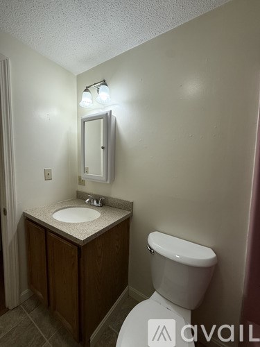 A bathroom with a toilet, sink, and mirror.