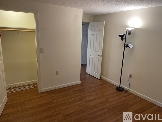 A kitchen with a black refrigerator, wooden cabinets, and a window with blinds.