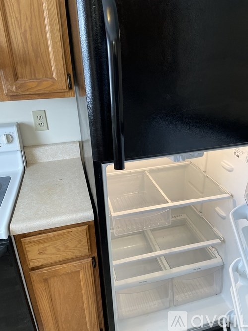 A black refrigerator with the door open and a white countertop beneath it.