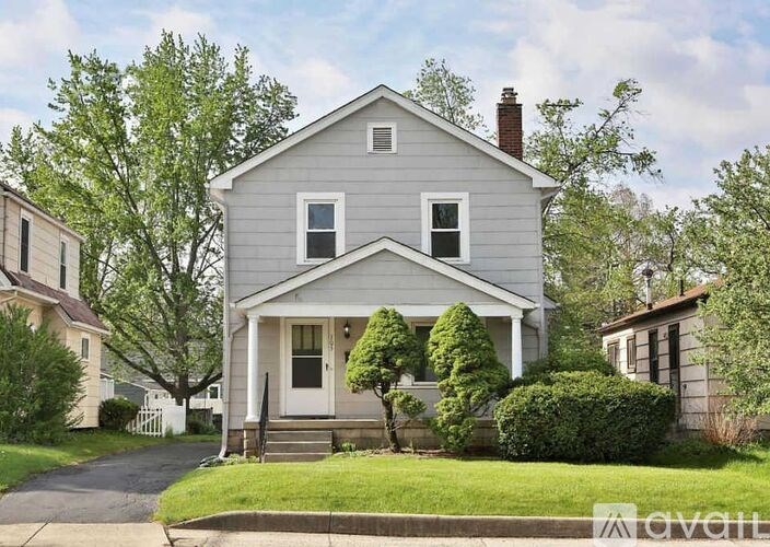 A two-story house with a front porch and a white picket fence.
