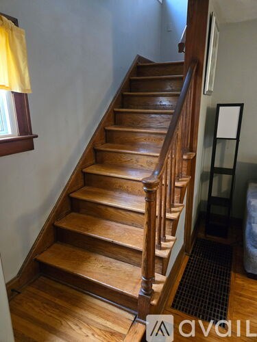 A wooden staircase with a black mat on the floor.