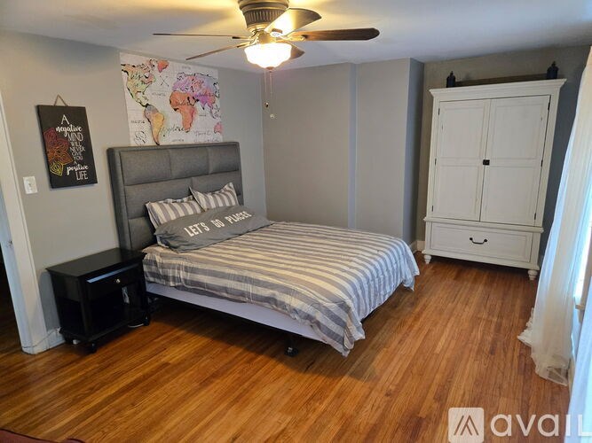 A bedroom with a bed, a ceiling fan, and a cabinet.