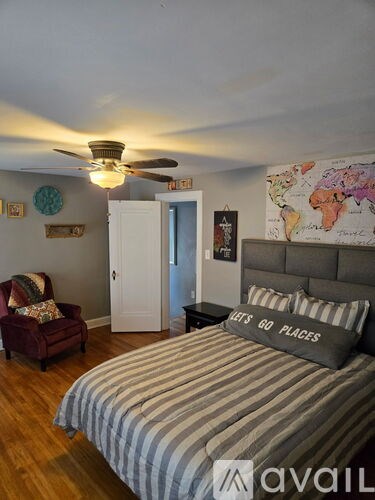 A bedroom with a bed, a chair, and a world map on the wall.