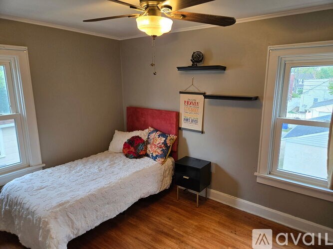 A bedroom with a bed, a ceiling fan, and a window.