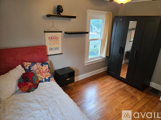 A bedroom with a bed, a window, and a sign on the wall.