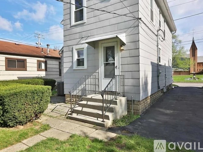 A house with a grey facade and a white door is for sale.