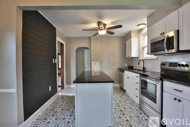 A kitchen with a black countertop and white cabinets.