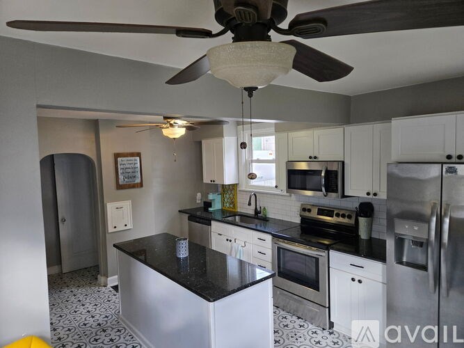 A kitchen with a black countertop and white cabinets.