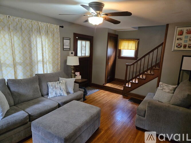 A living room with a grey couch and a wooden staircase.