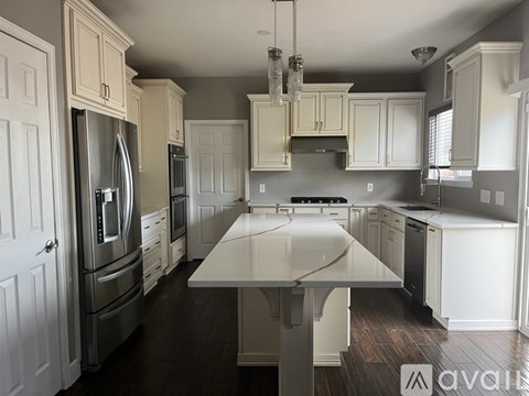 A kitchen with a white island and stainless steel appliances.