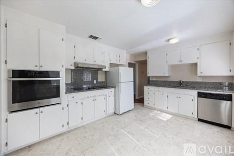 A kitchen with white cabinets and a marble floor.