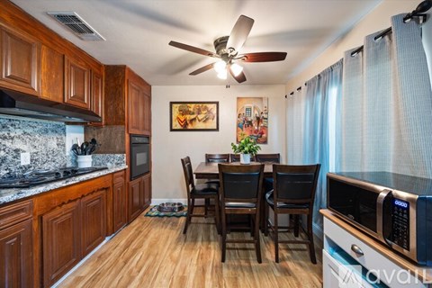 A kitchen with wooden cabinets and a dining table with chairs.