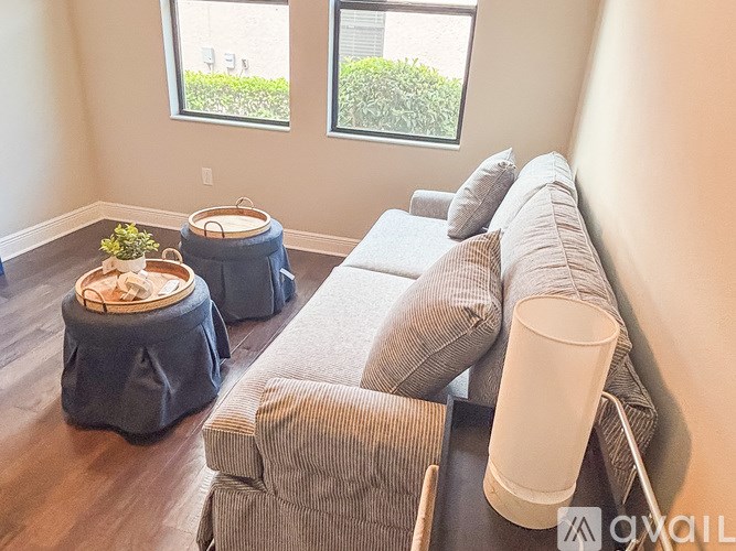 A living room with a grey couch and a plant on a table.