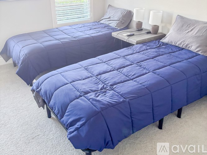 Two beds with blue comforter and pillow.