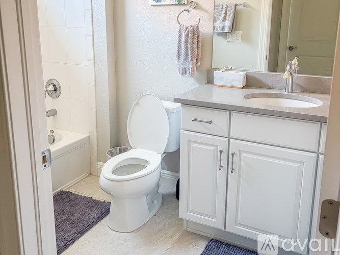 A white toilet is in a bathroom with a white cabinet and a white sink.
