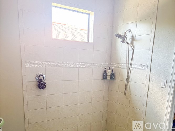 A shower area with a shower head and a window.