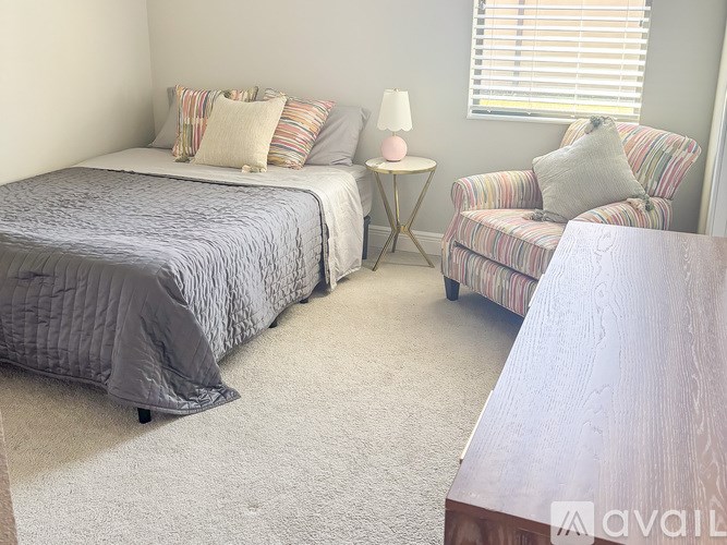 A bedroom with a bed, a chair, and a nightstand.