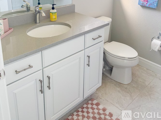 A bathroom with a sink, toilet, and cabinets.