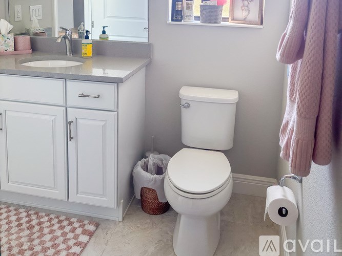A white toilet sits in a bathroom next to a sink and a cabinet.